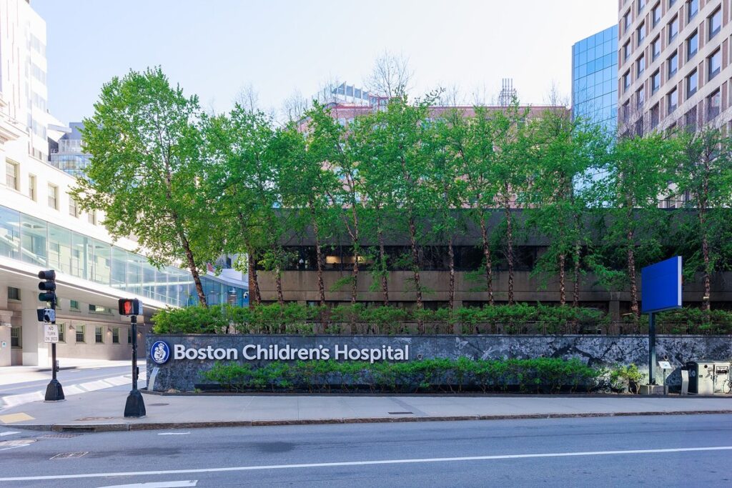 The Boston Children's Hospital sign on Longwood Avenue in Boston, with trees and hospital buildings behind it