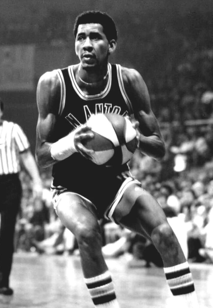 George Gervin in a San Antonio Spurs jersey holding a basketball, circa mid-1970s