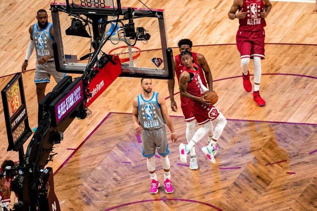 Ja Morant with the ball in a red jersey, with Stephen Curry nearby, during the 2022 NBA All-Star Game
