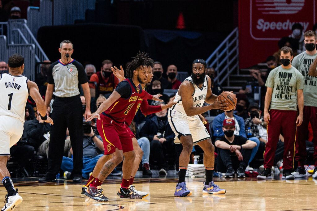 James Harden holds the ball against Cavaliers defenders as a referee watches in Cleveland