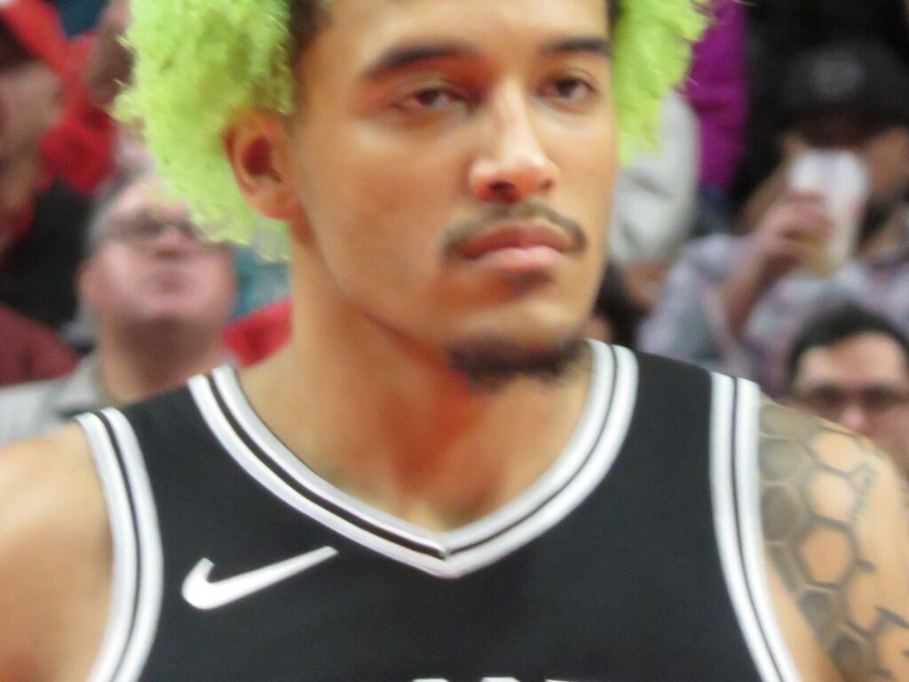 Jeremy Sochan, with bright green hair, in a black San Antonio Spurs jersey during a game in Portland