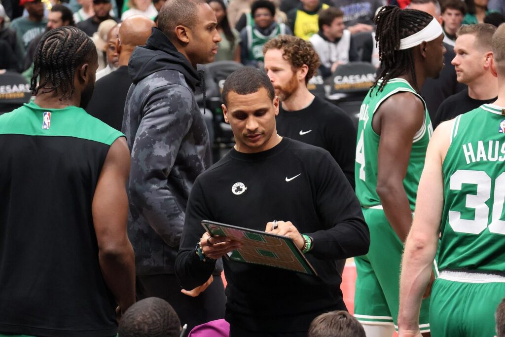 Celtics coach Joe Mazzulla draws on a clipboard during a timeout huddle