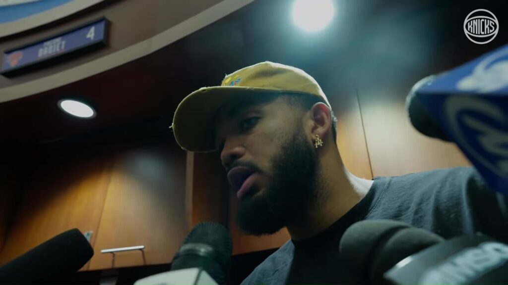 Karl-Anthony Towns in a tan cap speaking to reporters in the Knicks locker room at Madison Square Garden