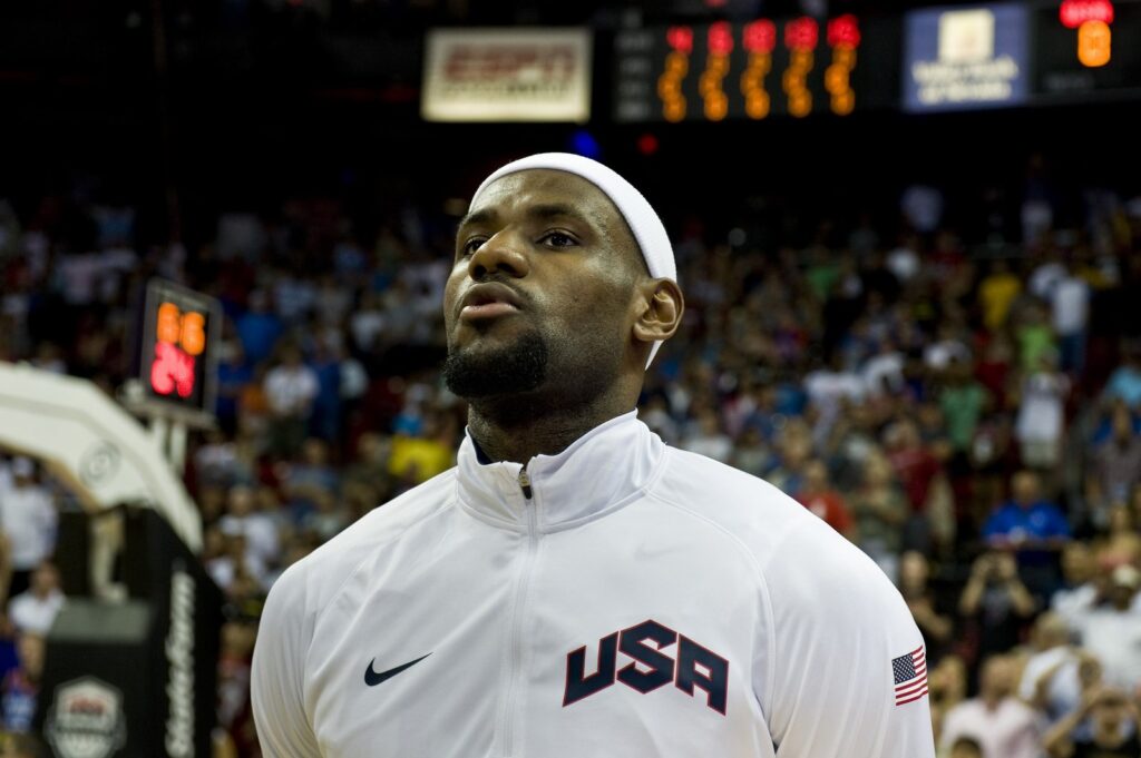 LeBron James in a white USA warm-up jacket listening to the national anthem before an exhibition game in Las Vegas