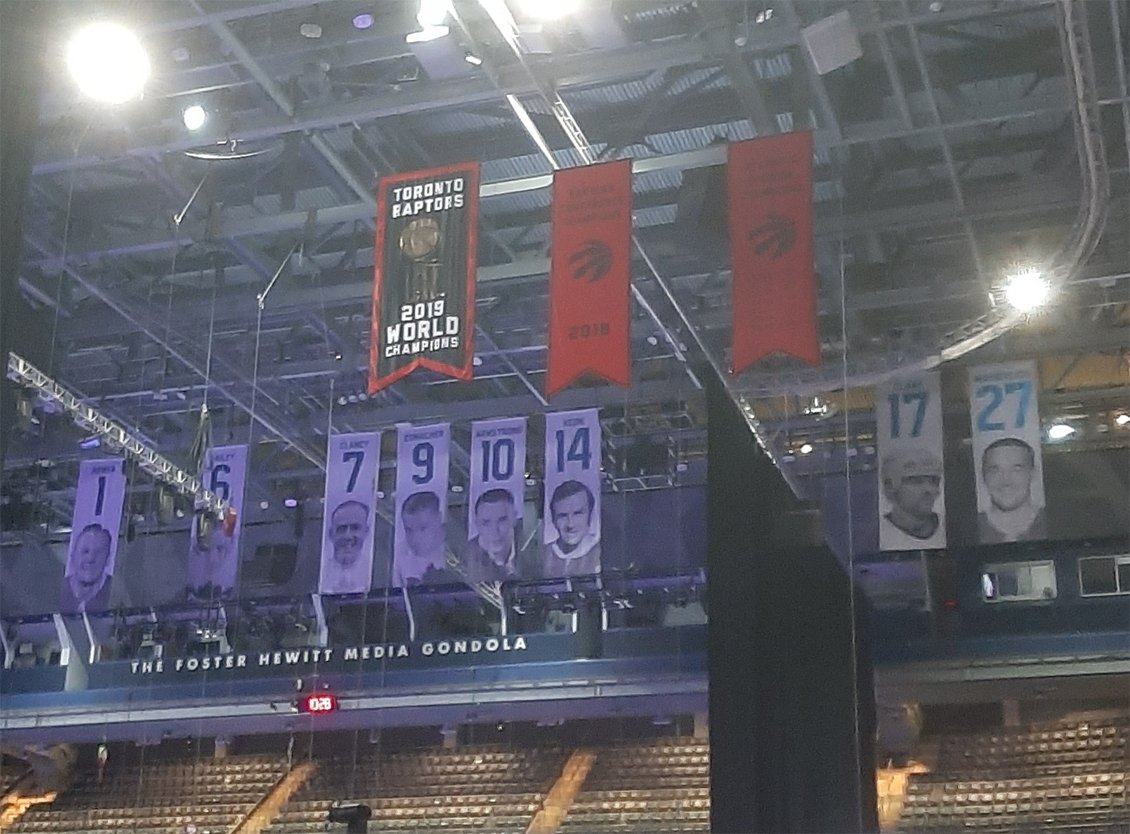 Toronto Raptors and Maple Leafs banners, including the Raptors 2019 championship banner, hanging in the rafters of Scotiabank Arena