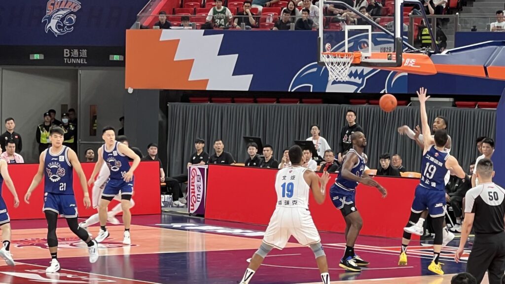 Shanghai Sharks players in light blue jerseys competing against the Beijing Ducks in a CBA game