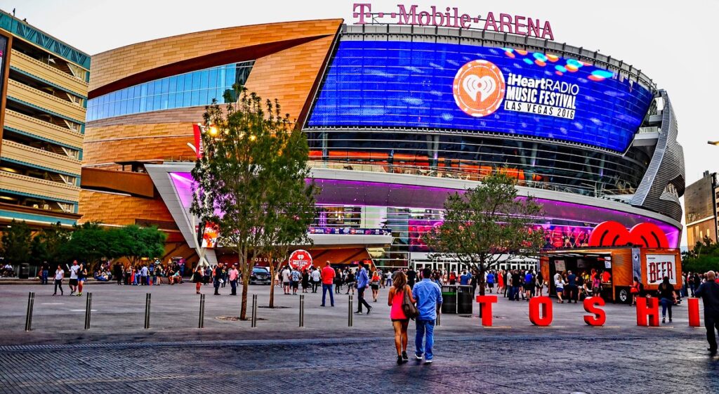 T-Mobile Arena in Las Vegas at dusk, with crowds walking on the plaza outside