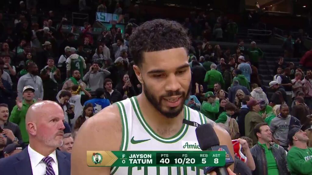 Jayson Tatum in a white Celtics jersey during his on-court interview after beating the Nets in overtime